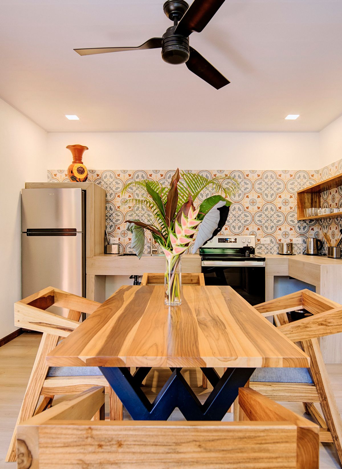 Vase with tropical leaves on the wooden table in the kitchen of the Raisa apartment