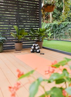 &Aacute;rea exterior para yoga con esterilla naranja, pesas y plantas tropicales